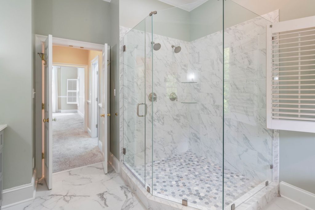 Porte de douche vitrée dans une cabine de douche en marbre