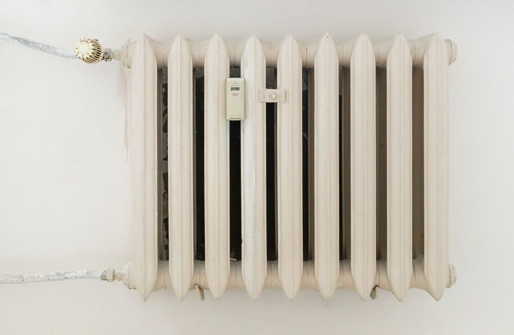 Radiateur blanc avec tuyaux et robinet thermostatique apparents