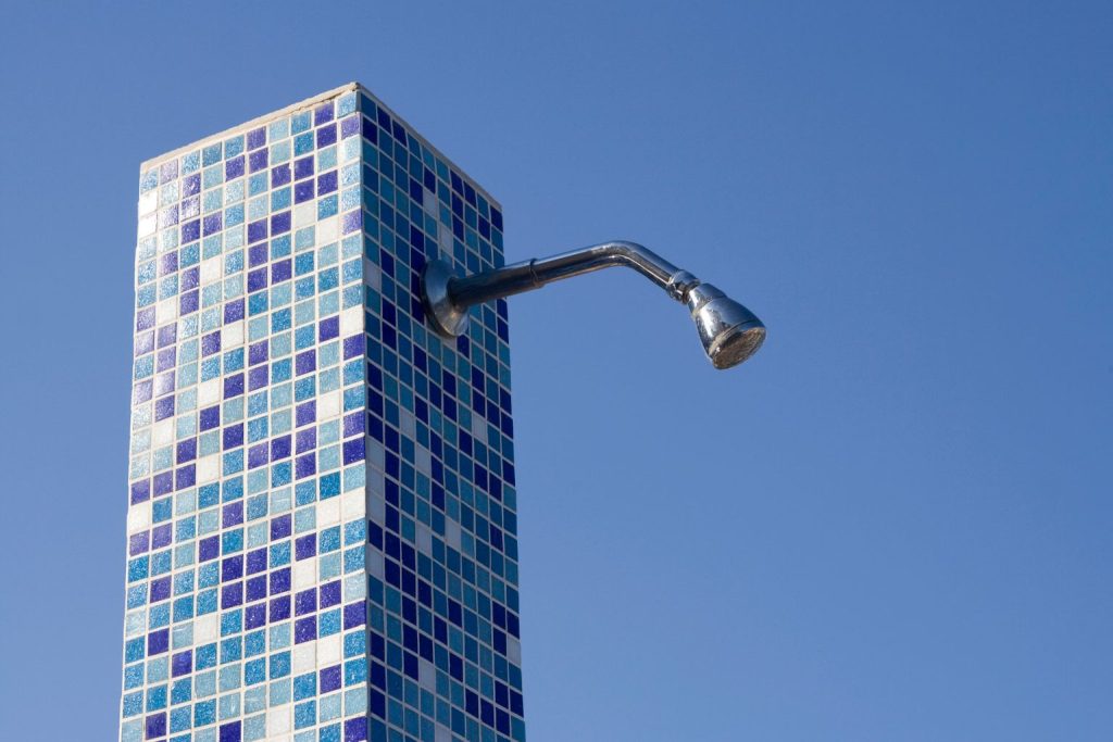 Douche extérieure carrelée en mosaïque avec pomme de douche fixée sur colonne