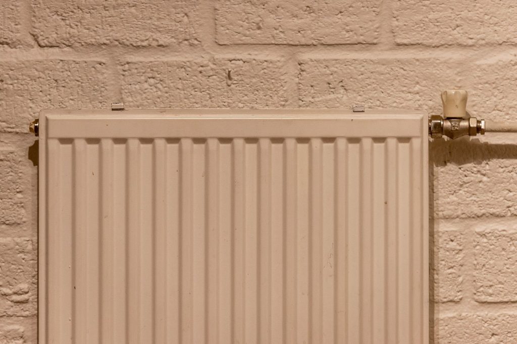 Radiateur à eau chaude fixé au mur avec vanne de réglage visible
