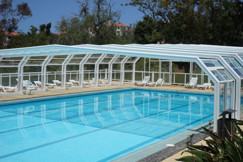Abri télescopique transparent recouvrant une piscine extérieure