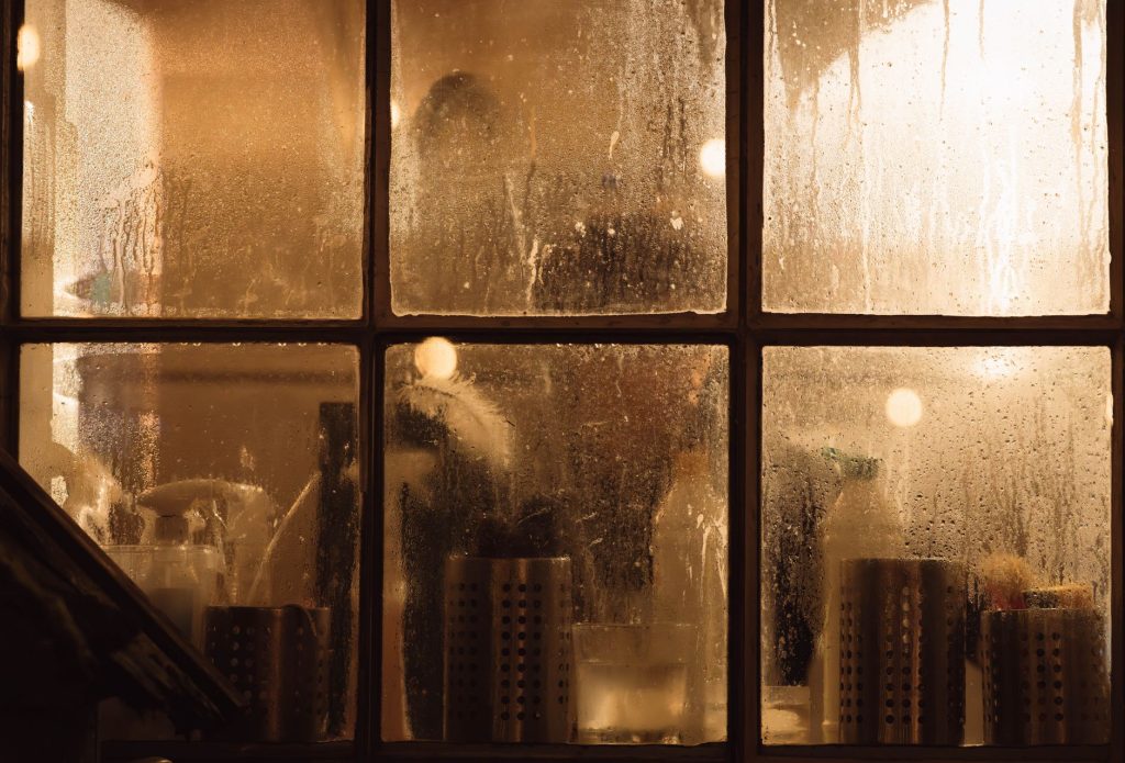 Vitres couvertes de buée par la condensation devant un intérieur éclairé