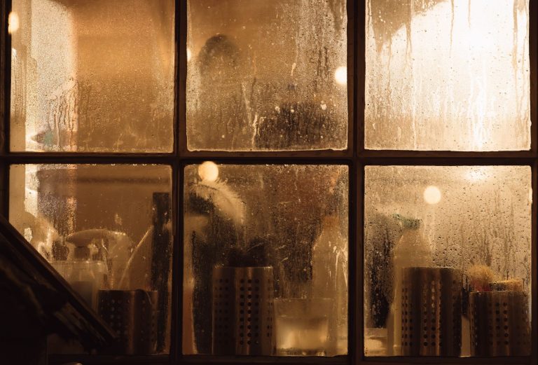 Vitres couvertes de buée par la condensation devant un intérieur éclairé