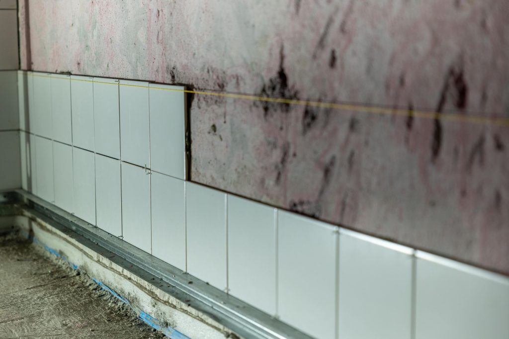 Mur de salle de bain dont l'ancien carrelage est en cours de dépose