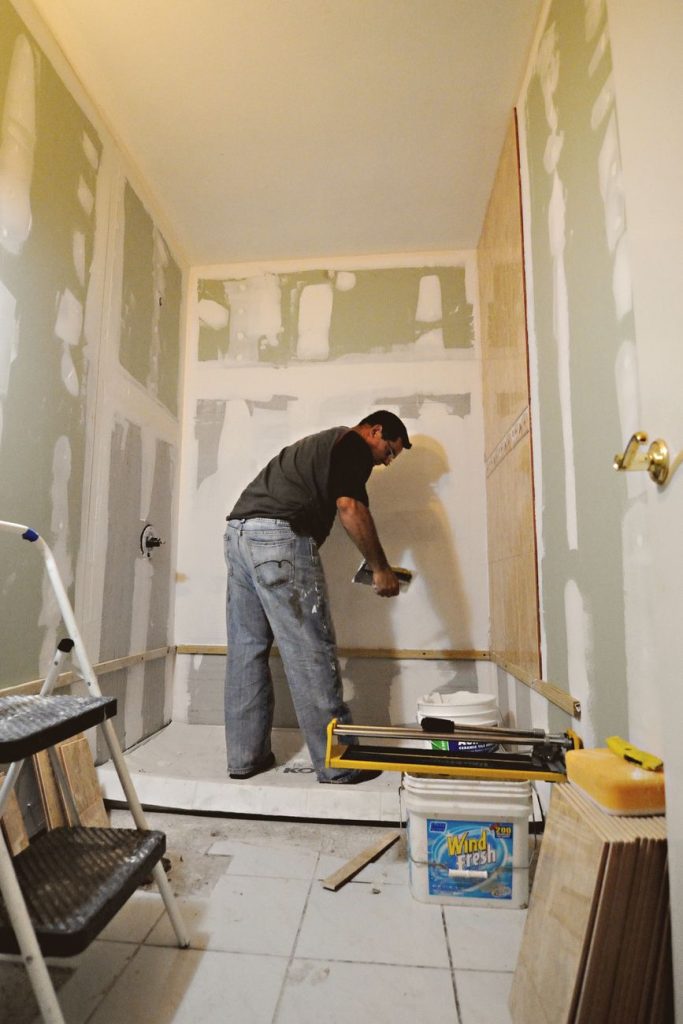 Artisan réalisant les joints d'un doublage en plaques de plâtre dans une salle de bain en rénovation