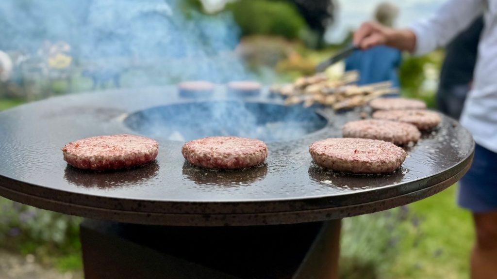 Steaks hachés cuisant sur une plancha ronde en extérieur