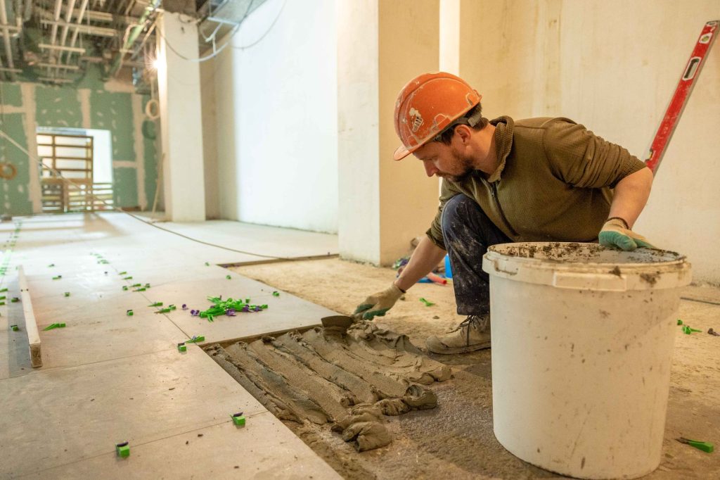 Carreleur posant des carreaux de sol sur un lit de mortier lors d'une rénovation