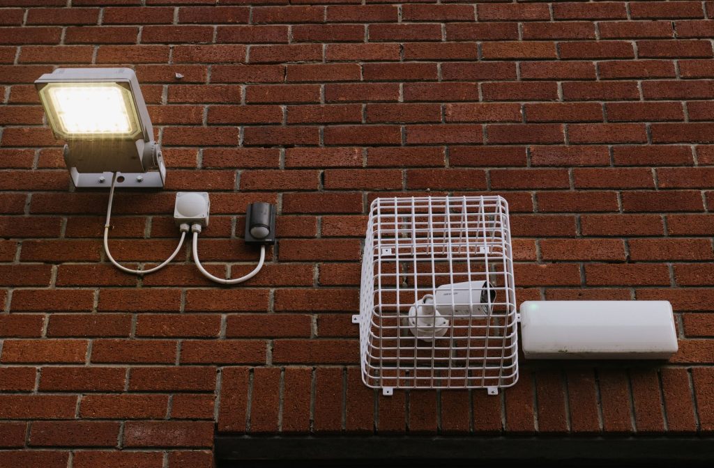 Projecteur LED extérieur fixé sur un mur de briques avec son câblage