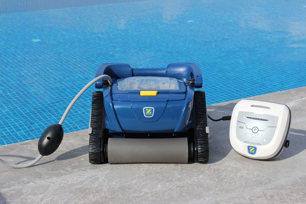Robot de piscine électrique avec son boîtier d'alimentation et son câble flottant au bord du bassin