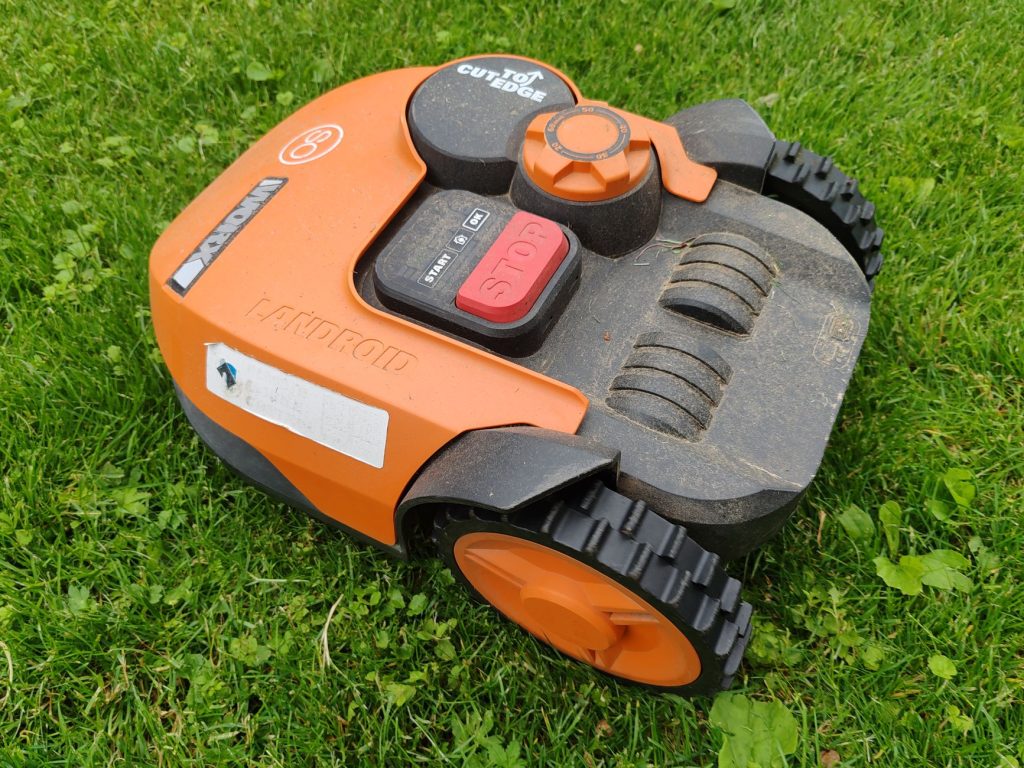 Robot tondeuse orange posé sur une pelouse