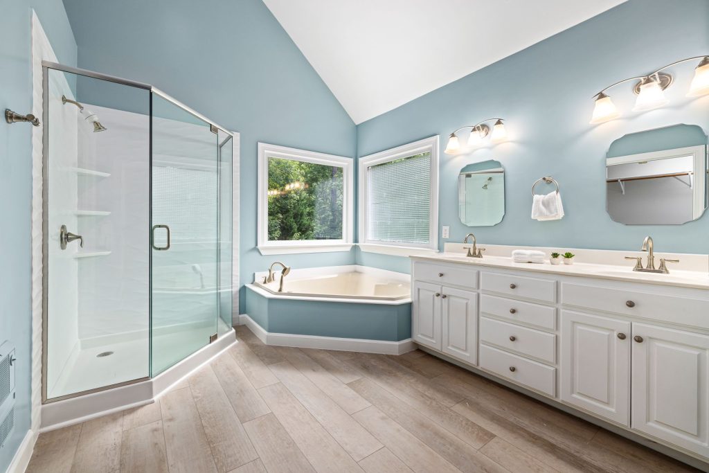 Salle de bain réunissant une cabine de douche vitrée et une baignoire d'angle