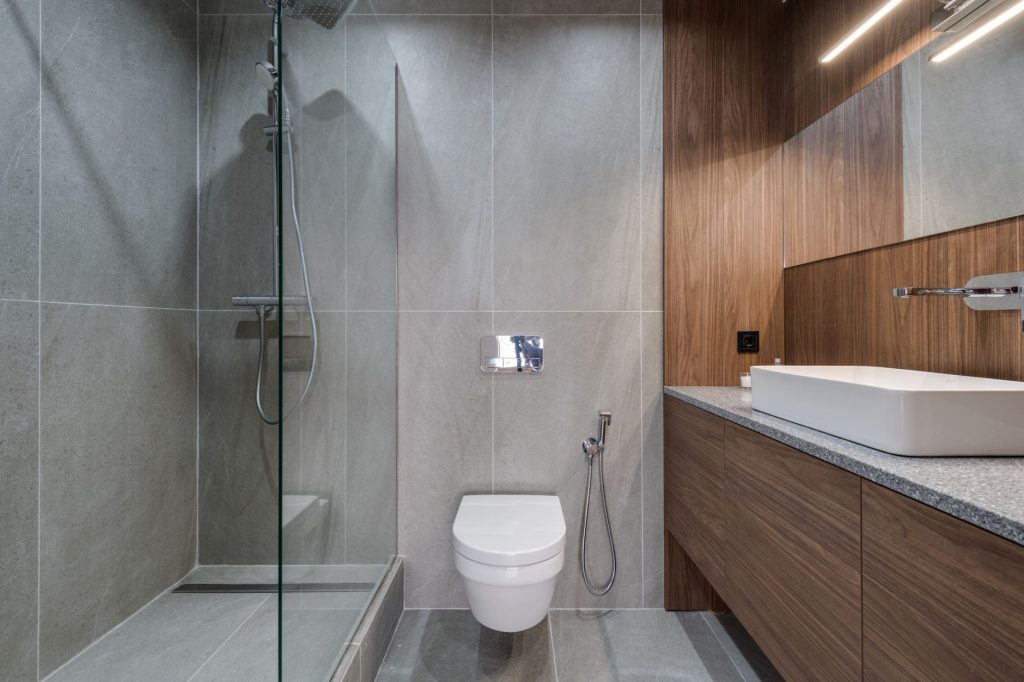 Salle de bain rénovée avec douche à l'italienne vitrée, WC suspendu et meuble vasque en bois