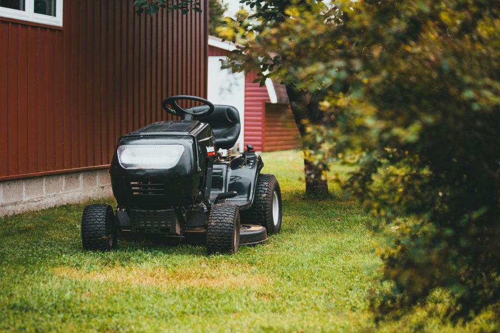 Tracteur tondeuse garé sur une pelouse près d'un bâtiment