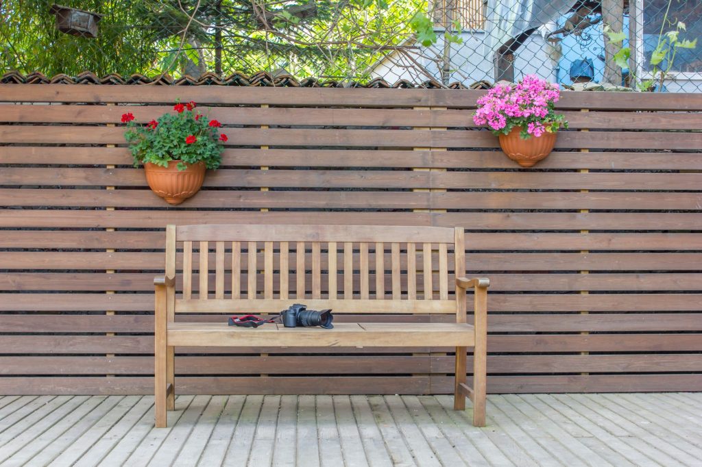 Claustra en lames de bois horizontales derrière un banc sur une terrasse en bois