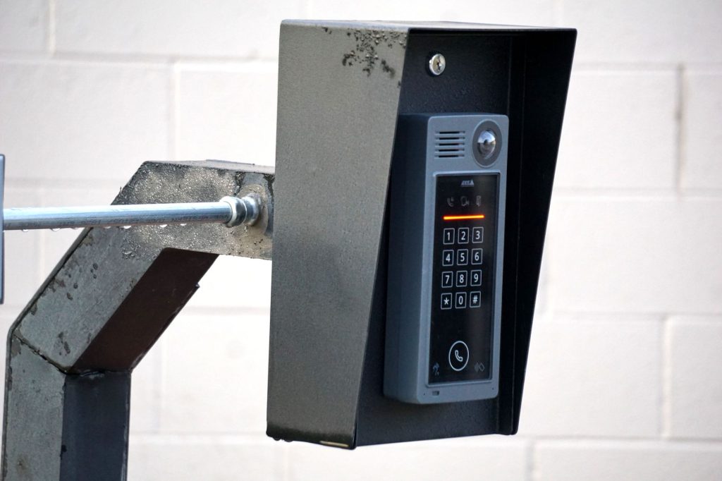 Platine de rue avec clavier à code et interphone fixée près d'un portail