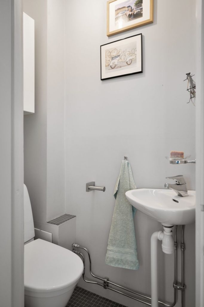 Petit lave-mains mural dans des toilettes avec ses tuyaux d'alimentation et d'évacuation apparents