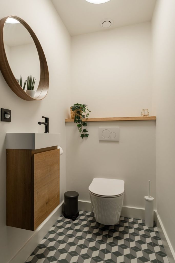 Toilettes avec WC suspendu et meuble lave-mains en bois surmonté d'un miroir rond