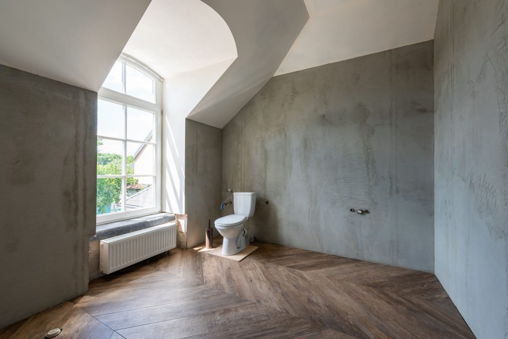 Pièce d'eau sous combles aux murs recouverts d'un enduit effet béton gris, avec sol en parquet