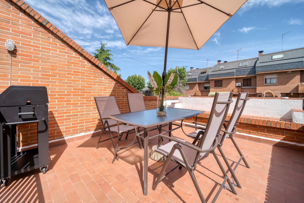 Parasol ouvert au-dessus d'une table et de chaises sur une terrasse en carreaux de terre cuite