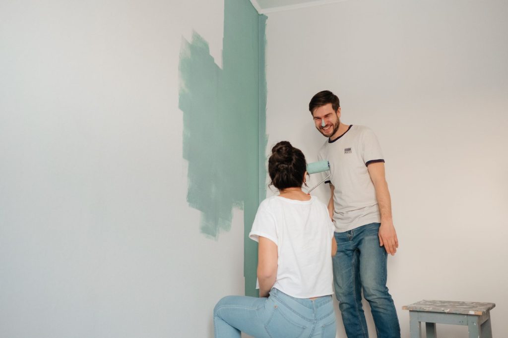 Couple appliquant une peinture vert d'eau au rouleau sur un mur blanc