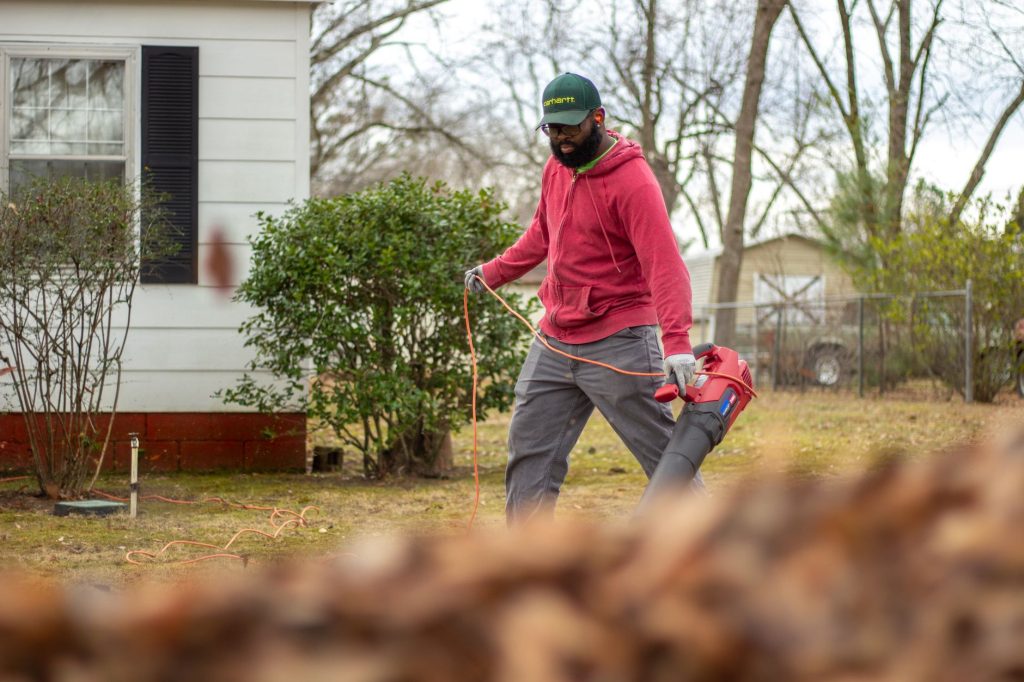 Homme utilisant un souffleur de feuilles électrique dans un jardin à l'automne