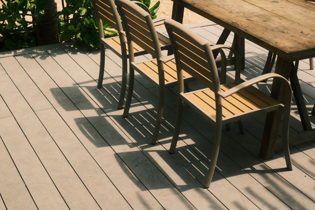 Terrasse en lames composites gris clair avec table et chaises de jardin en bois et aluminium