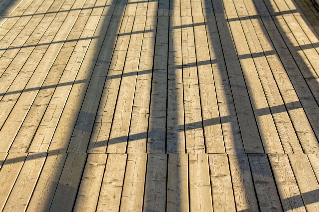 Terrasse neuve en lames de pin traité baignée par la lumière du soleil
