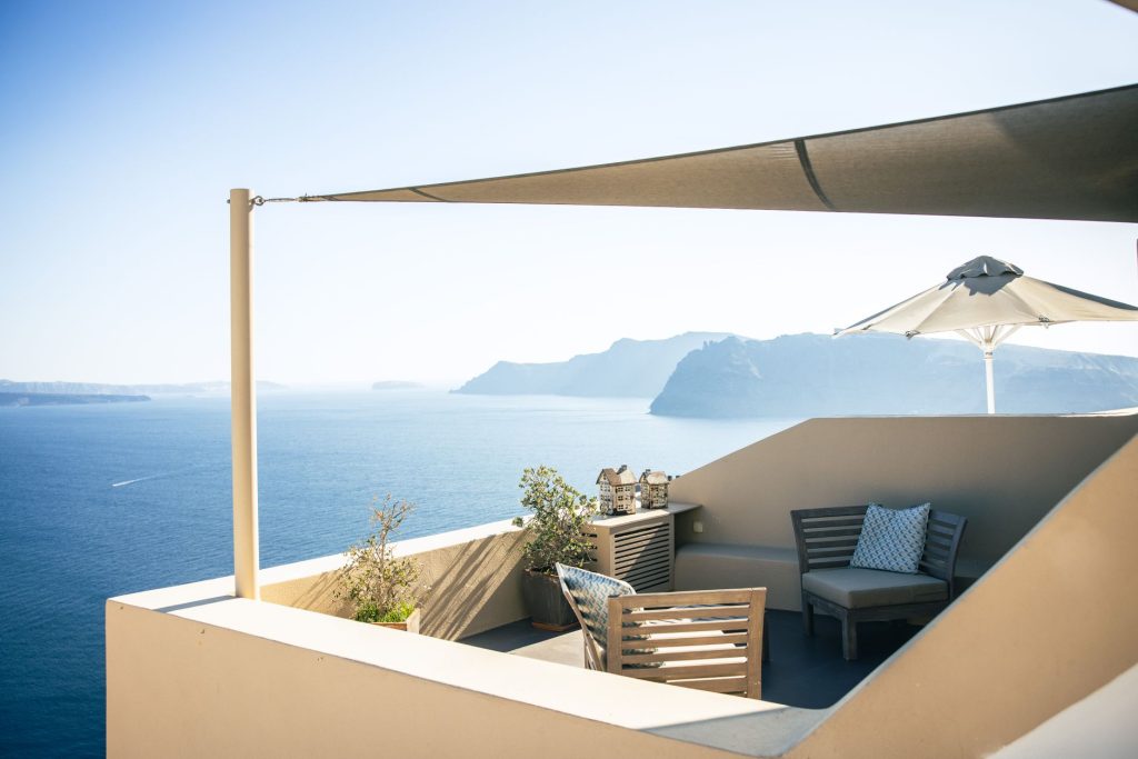 Voile d'ombrage tendue au-dessus d'un coin salon sur une terrasse avec vue sur la mer