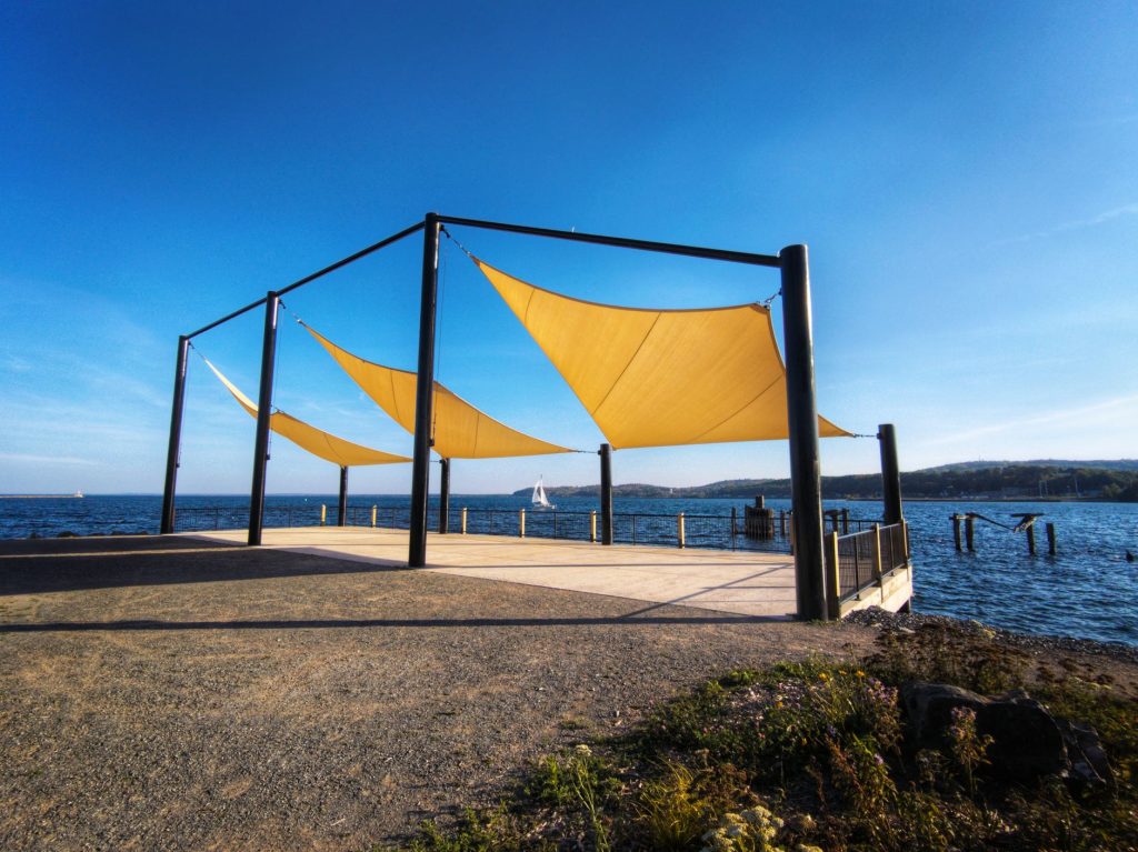Voiles d'ombrage triangulaires jaunes tendues entre des mâts métalliques inclinés